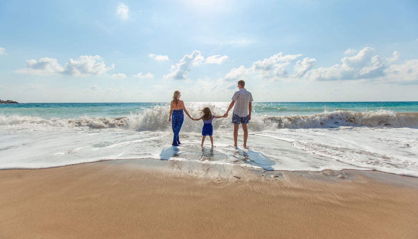 Young family standing on the beach with waves splashing up
