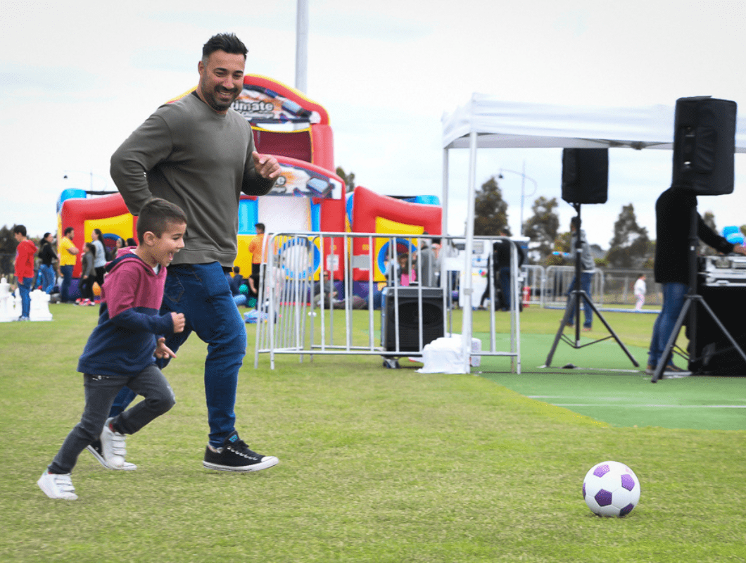 True North, Greenvale community event, father and son kicking soccer ball.